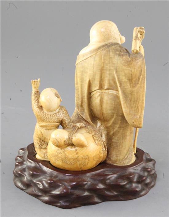A Japanese ivory okimono of Hotei and a boy, early 20th century, height 16.5cm, wood stand